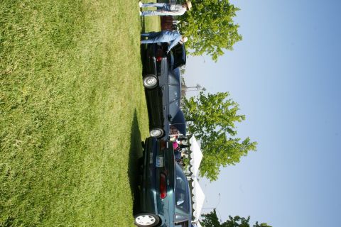 1992 Ford Taurus - Two sedans, one identified as a 1992 Ford Taurus, are parked on a grassy field under a clear blue sky.
