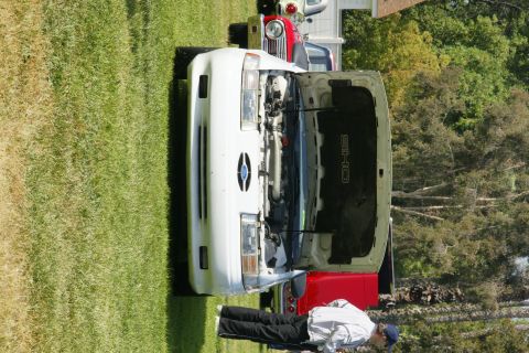 1992 Ford Taurus - A white 1992 Ford Taurus SHO is displayed with its hood open, alongside other vehicles on a sunny day.
