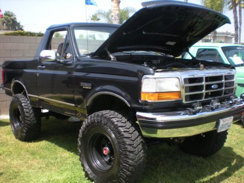 1979 Ford Bronco - This black Ford Bronco features a lifted suspension and its hood is open, revealing the engine bay.