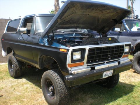 1979 Ford Bronco - A lifted black 1979 Ford Bronco sits with its hood open, parked next to another vehicle.
