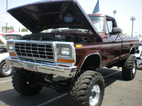 1979 Ford Bronco - This lifted Ford F-Series truck has its hood open, revealing the engine and a prominent chrome grille with a Ford Trucks badge.