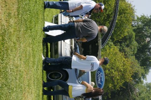 1992 Ford Taurus - A group of people gather around a 1992 Ford Taurus at an outdoor event.