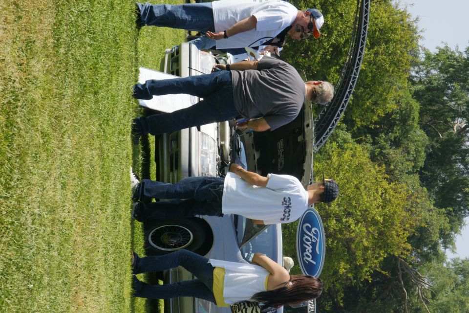 People looking at a 1992 Ford Taurus with the hood open. A Ford logo is visible