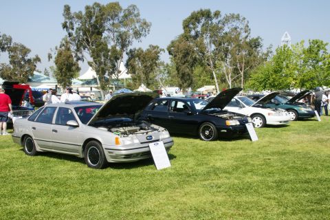 1992 Ford Taurus - A silver 1992 Ford Taurus is displayed with its hood open at a car show, alongside other vehicles.