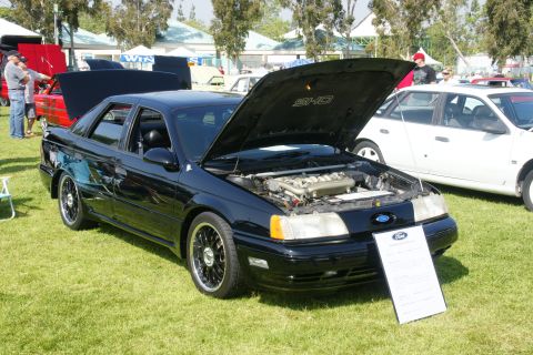 1992 Ford Taurus - A black Ford Taurus SHO is displayed with its hood open, revealing the engine, at an outdoor car show.