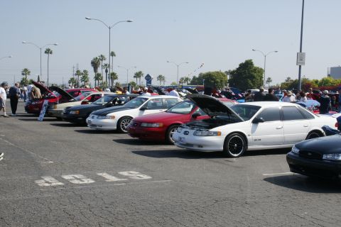 1992 Ford Taurus - A line of Ford Tauruses are displayed at a car show, with one white model open for viewing.