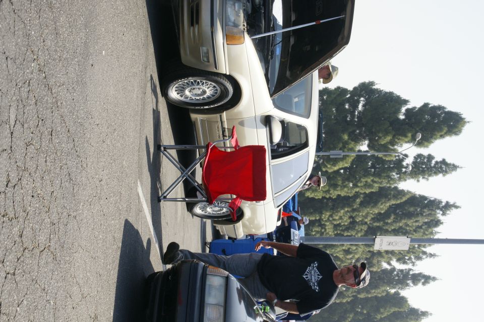 Beige 1992 Ford Taurus sedan with hood open, parked on asphalt, red folding chair in front