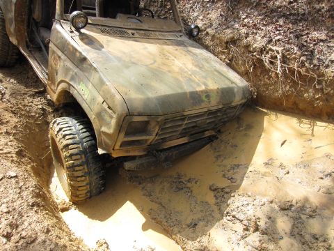 1993 Ford Bronco - This off-road vehicle is stuck in a muddy ditch, with its front tire submerged.
