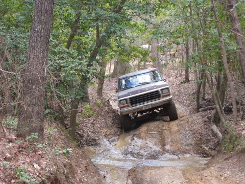 1993 Ford Bronco - Ford Bronco tackling a challenging muddy path through a wooded area.