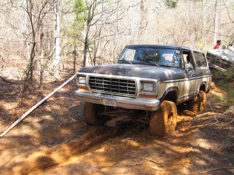 1993 Ford Bronco - A 1978 Ford Bronco navigates a muddy off-road trail, with another vehicle visible in the background.