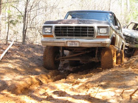 1993 Ford Bronco - This lifted 1978 Ford Bronco navigates a muddy trail, with another vehicle visible behind it.