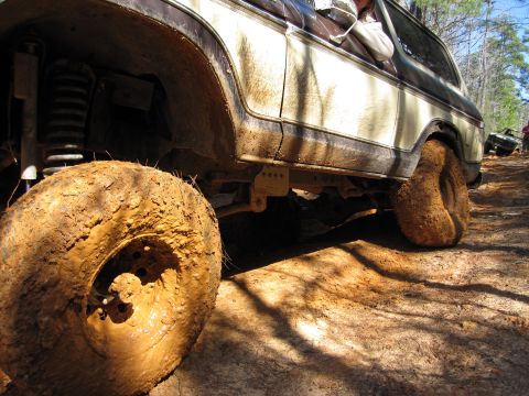 1993 Ford Bronco - This heavily soiled 1978 Ford Bronco navigates a muddy off-road course, with another vehicle visible in the background.