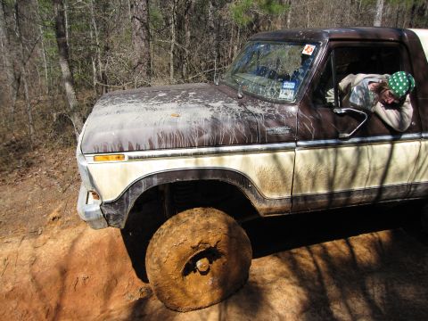 1993 Ford Bronco - This 1978 Ford Bronco is shown off-road with a mud-caked tire and a driver visible through the window.