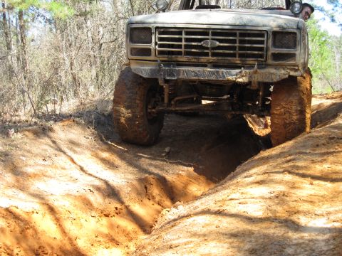 1993 Ford Bronco - This modified SUV tackles a challenging off-road trail with its front end angled into a deep dirt rut.