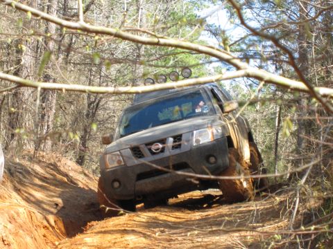 1993 Ford Bronco - Off-road vehicle navigating a challenging dirt path through a wooded area.