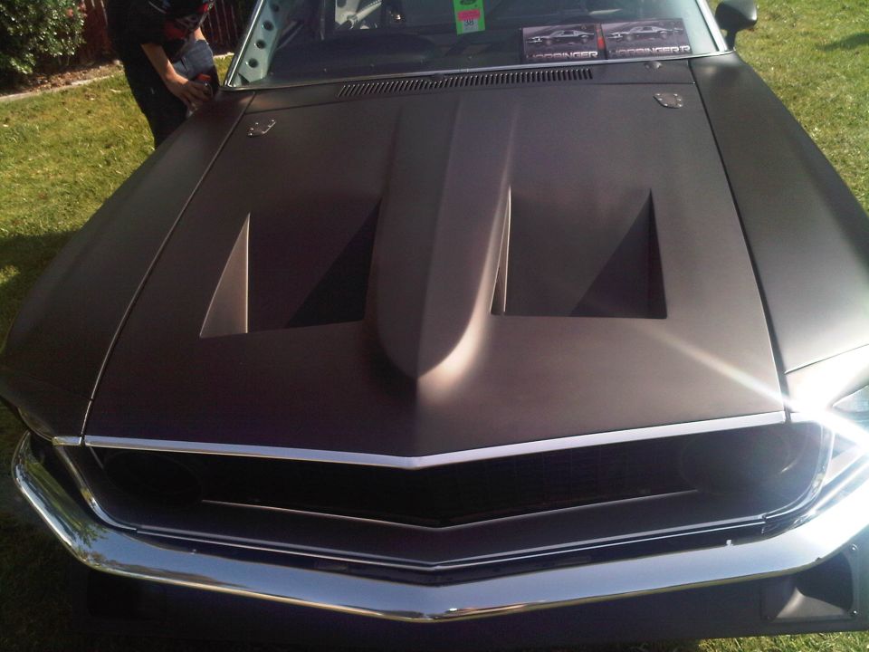 Dark matte hood with a large scoop and chrome grille on a car