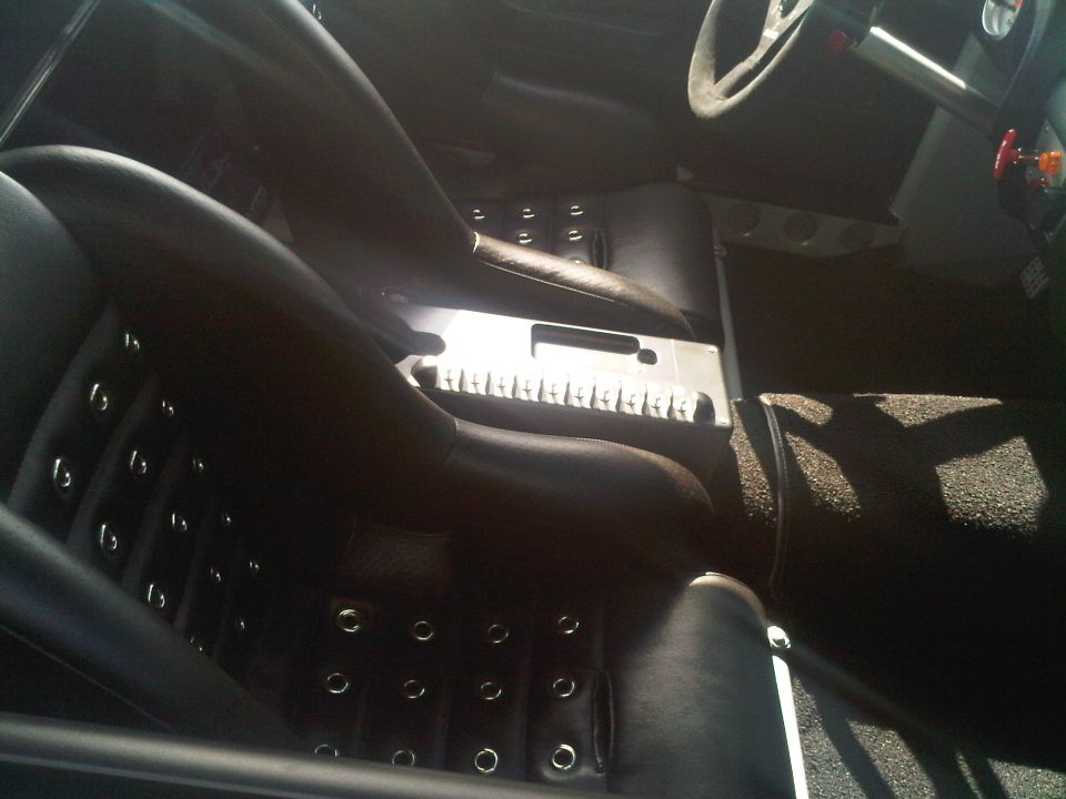 Black leather bucket seats with grommets, metal center console, and steering wheel