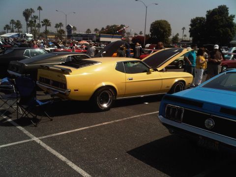 1986 Ford Bronco - A yellow 1971 Ford Mustang Mach 1 is displayed with its hood open at an outdoor car show.