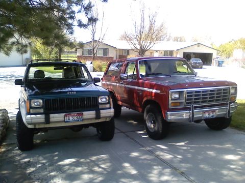 1981 Ford Bronco - Two SUVs, a red Ford Bronco and a green Jeep Cherokee, are parked in a driveway.