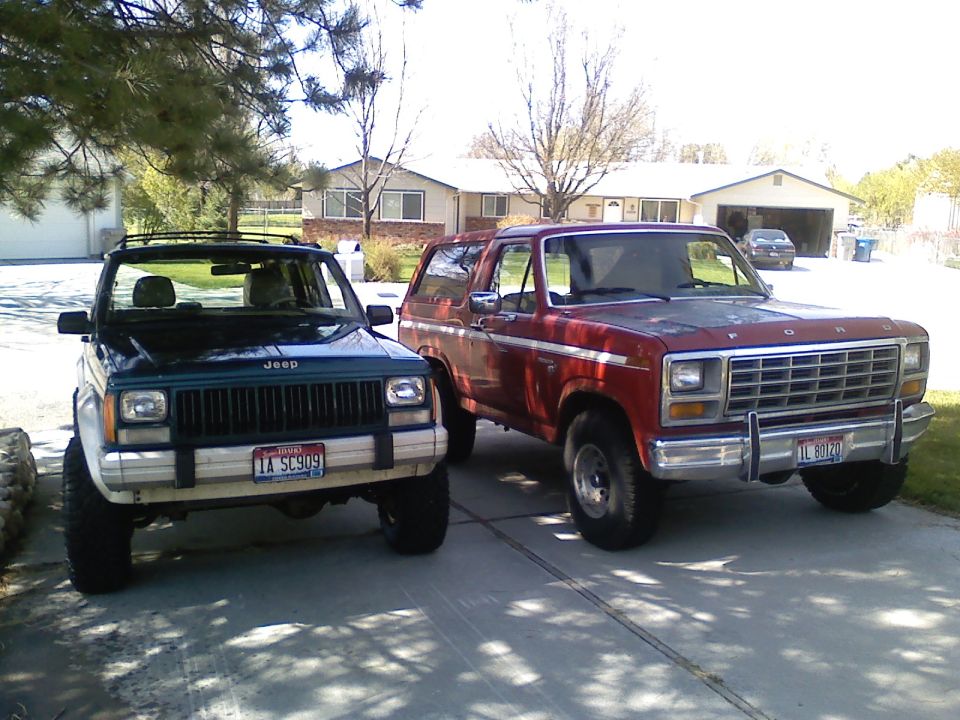 Red 1980 Ford Bronco and green Jeep Cherokee parked side-by-side