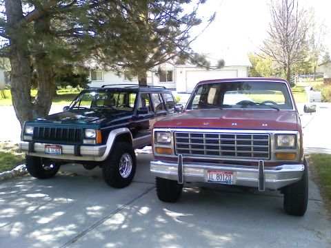 1981 Ford Bronco - A red Ford truck and a green Jeep are parked in a driveway on a sunny day.