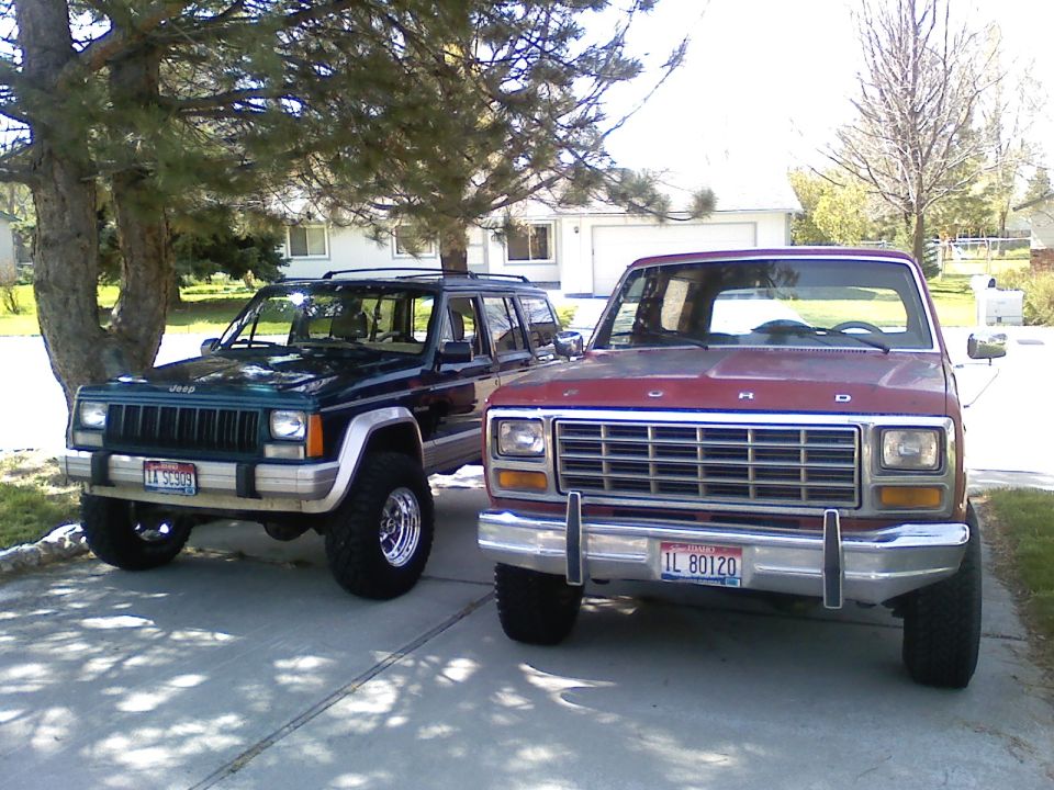 red Ford truck and green Jeep parked outside a house