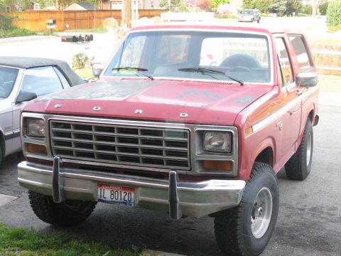 1981 Ford Bronco - A red Ford Bronco is parked in a driveway next to another vehicle.
