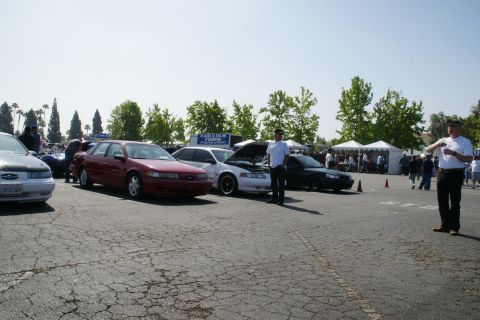 1992 Ford Taurus - A gathering of Ford Taurus vehicles, possibly at a car show, with attendees and tents visible.