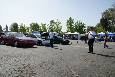 1992 Ford Taurus - Several Ford Tauruses are on display at an outdoor event with tents and people in the background.