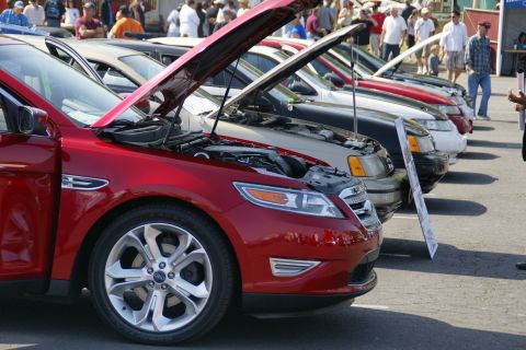 1992 Ford Taurus - A line of cars with hoods open, including a red Ford sedan in the foreground. The registry claims it is a 1992 Ford Taurus, but the body st…