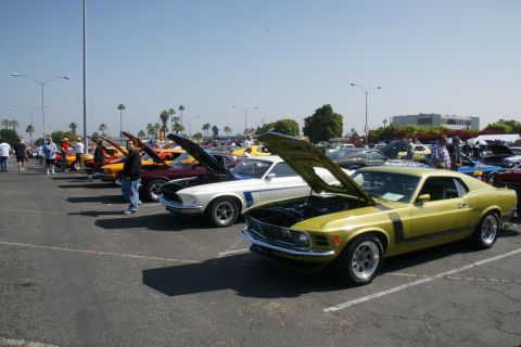 1992 Ford Taurus - A line of classic cars, including a yellow muscle car with its hood open, are displayed at an outdoor event.