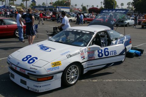 1992 Ford Taurus - Ford Probe race car with various sponsor decals and racing numbers is displayed at an event.