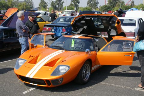 1992 Ford Taurus - An orange sports car with its doors open, parked at an outdoor event with other vehicles.