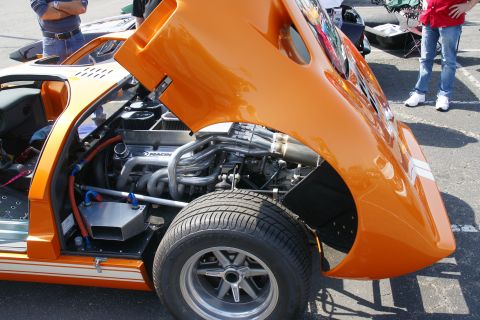 1992 Ford Taurus - Close-up of a custom orange sports car's engine bay with exposed V8 engine and headers.