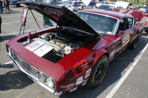 1992 Ford Taurus - A classic red race car is displayed with its hood open, revealing the engine compartment and various racing decals on its body.