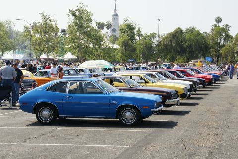 1992 Ford Taurus - A blue 1977 Ford Pinto coupe is seen from the side at a car show, parked in a row with other vehicles.