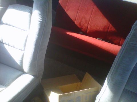 1978 Ford Bronco - The interior features light grey front seats and a red rear bench seat, with cardboard boxes visible in the cargo area.
