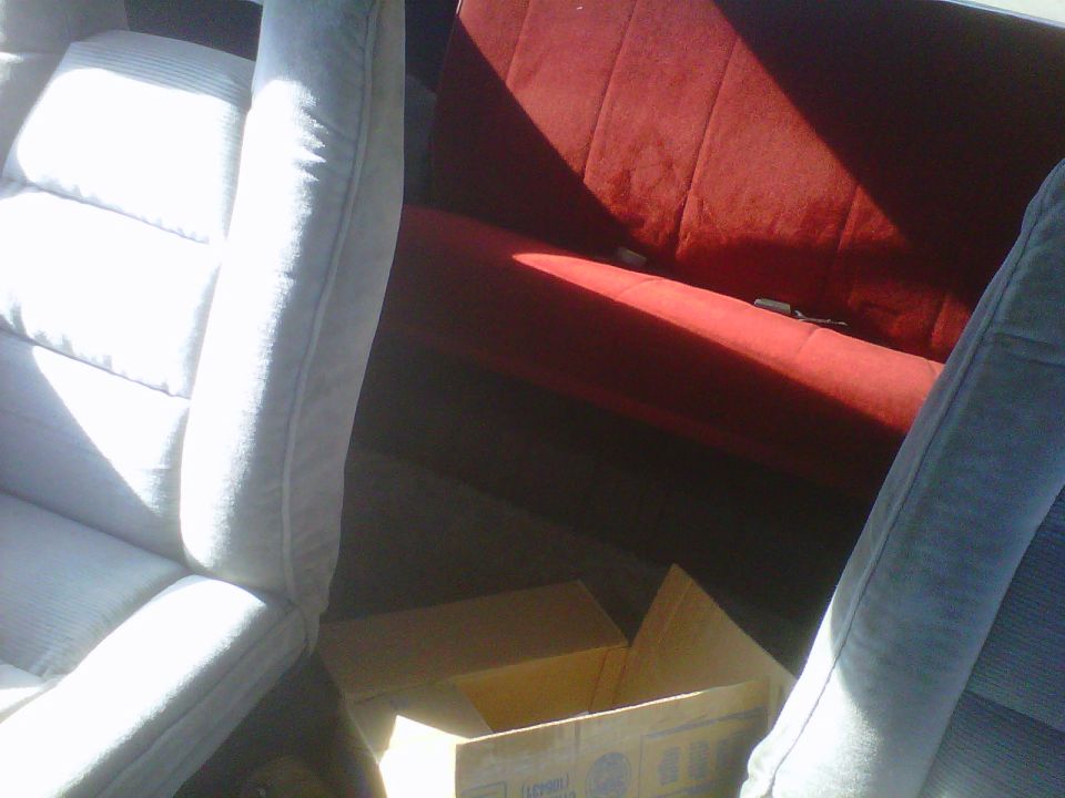 Interior view of vehicle with light grey and red seats, boxes in the back