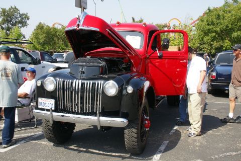1992 Ford Taurus - A classic truck with its hood and door open is displayed at an outdoor event with other vehicles and people present.