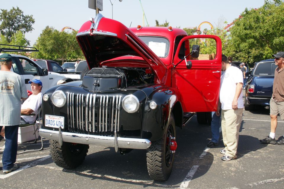 red and black vintage truck with hood and door open, people around it