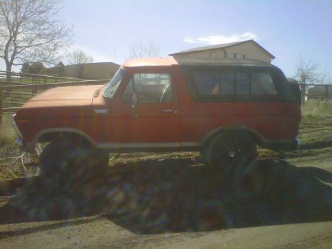 1978 Ford Bronco - This 1978 Ford Bronco is seen from the side, parked on a dirt lot with a spare tire mounted at the rear.