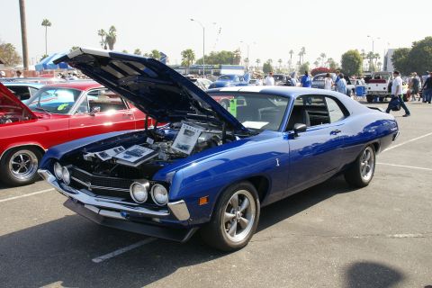 1992 Ford Taurus - A blue 1970 Ford Torino GT is displayed with its hood open at an outdoor car show.