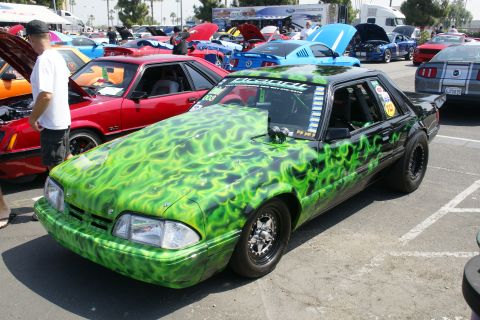 1992 Ford Taurus - This customized 1992 Ford Mustang features a striking green flame paint job and is displayed at a car show.