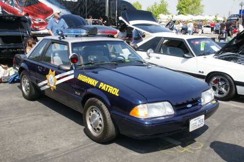 1992 Ford Taurus - A Ford Mustang police car is displayed at a car show, with another Mustang beside it.
