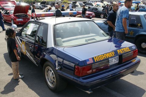 1992 Ford Taurus - A blue and white police car, likely a Ford Mustang, is parked outdoors with other vehicles.