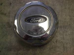 1976 Ford Torino - A chrome Ford hubcap is shown against a textured surface.