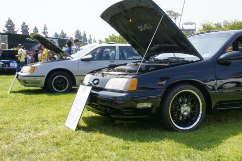 1992 Ford Taurus - Two Ford Taurus models, one black SHO and a silver sedan, are displayed with hoods open at an outdoor car show.