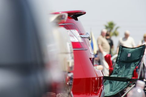 1992 Ford Taurus - Close-up of a red car's rear end at an outdoor event with people milling around.
