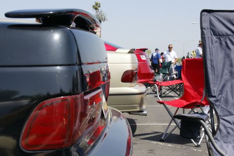 1992 Ford Taurus - A close-up of a black car's rear spoiler and taillight is shown, with other vehicles and attendees visible in the background at an outdoor…