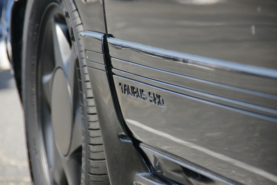 Black car door with "TAURUS SHO" badge visible, close-up side view